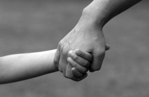 Parent holding child's hand in black and white photo